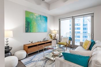 A living room with a large painting on the wall and a view of a cityscape through the windows.